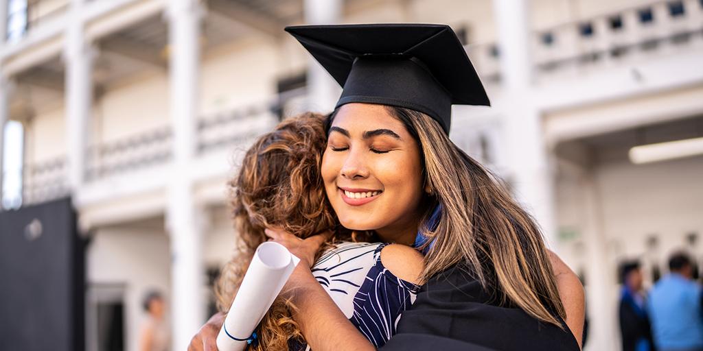 a young woman in a graduation cap hugs her mom