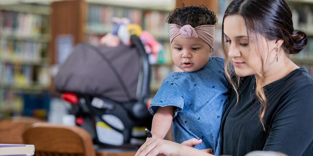 Mother holding daughter while studying