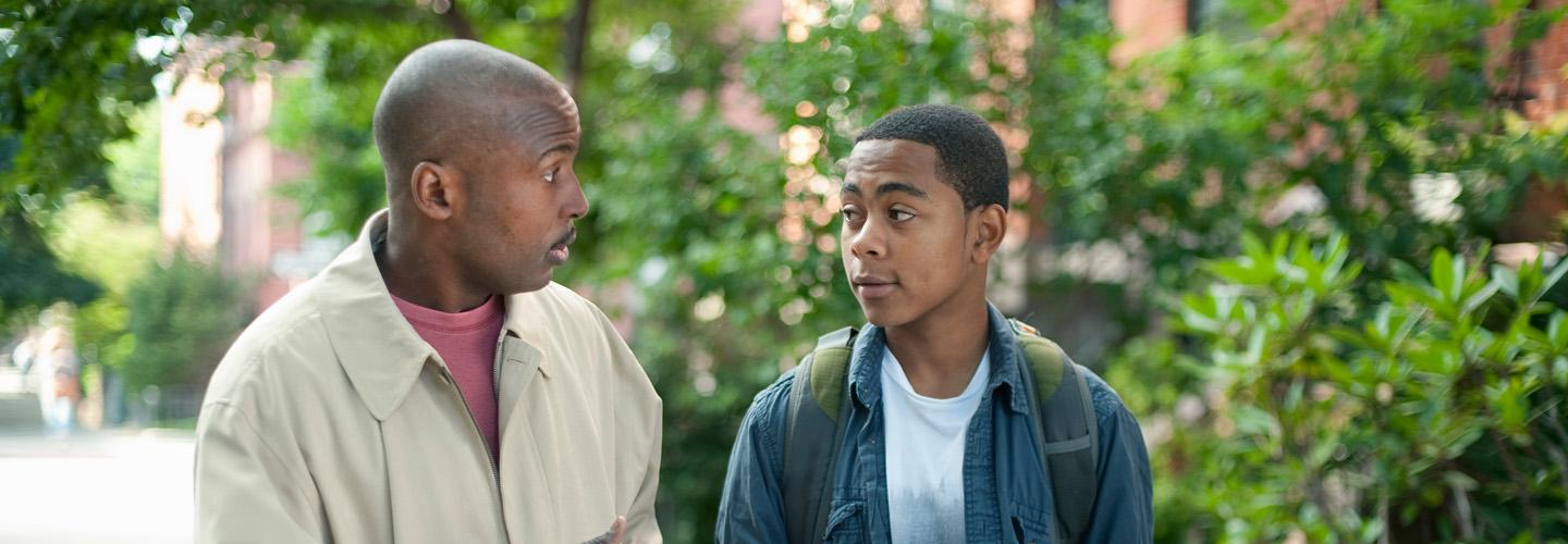 a teen boy and older man walk together