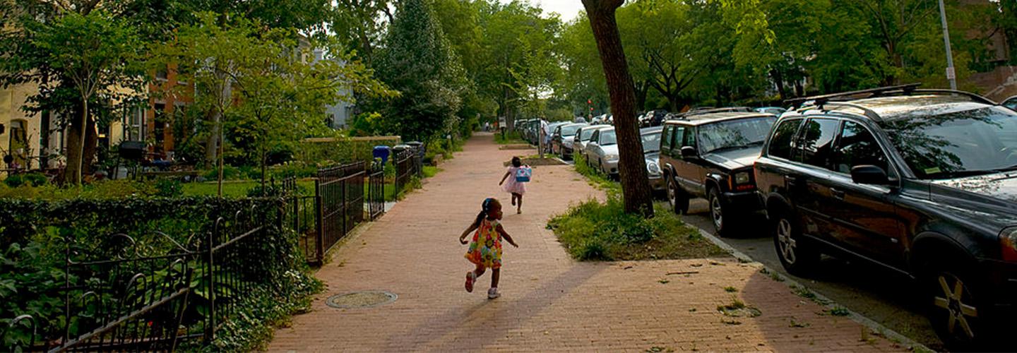 two young children run down the sidewalk