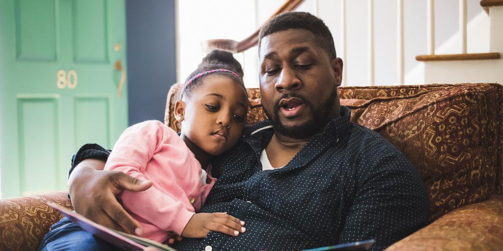 a father reads to his daughter