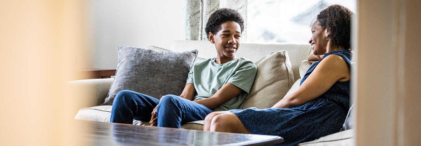 a mother and her teen son sit on a couch